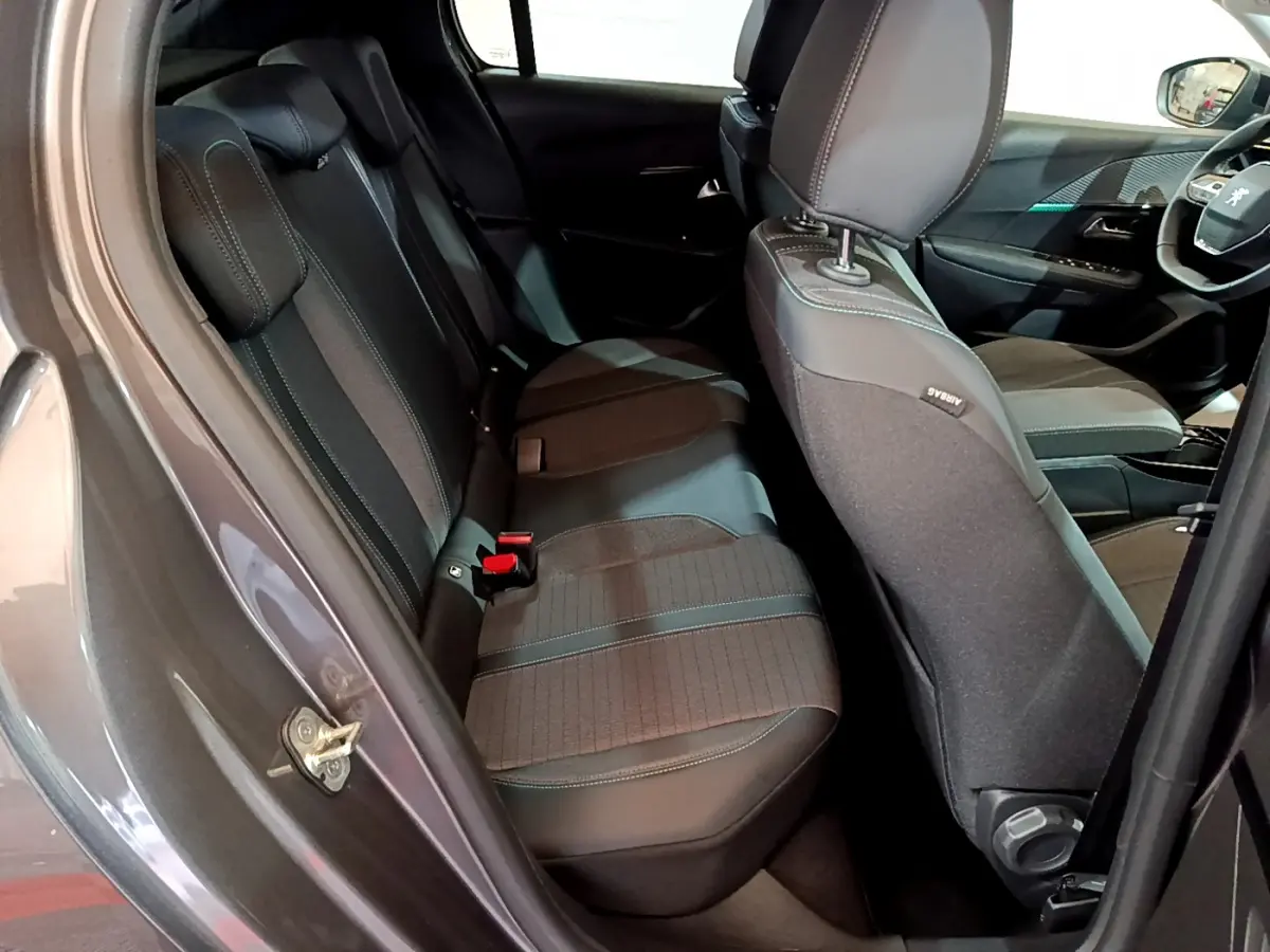 Vue intérieure côté gauche sur les sièges arrière et avant d’une Peugeot 208 gris foncé avec sellerie tissu et cuir.