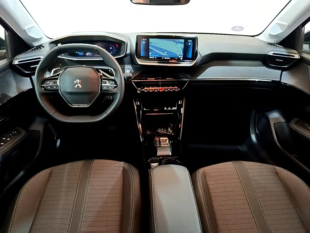 Intérieur Peugeot 208 2022 vu de face, tableau de bord noir avec écran tactile central et volant cuir compact.