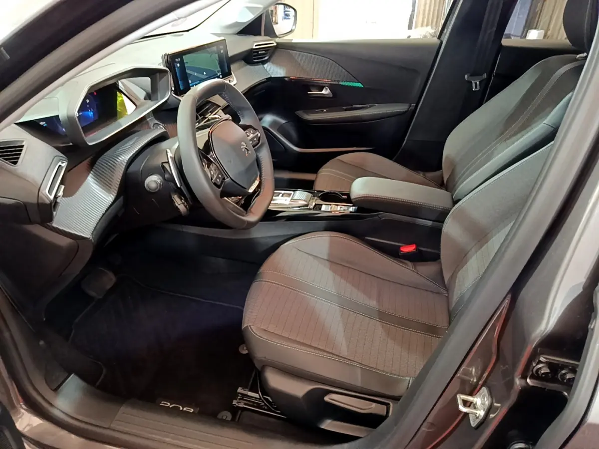 Intérieur avant droit de la Peugeot 208 gris foncé 2022, avec tableau de bord numérique et volant cuir multifonctions.