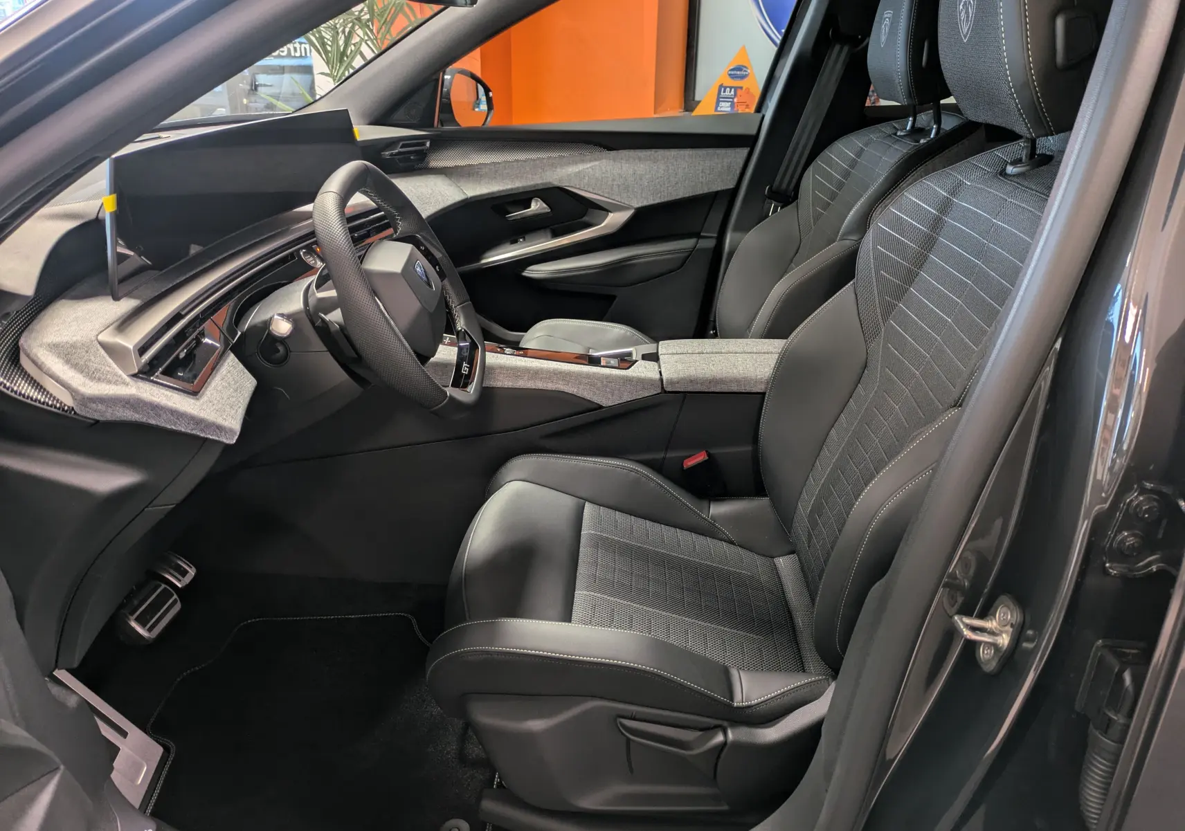 Intérieur côté conducteur du Peugeot 3008 Hybrid gris titane, avec sièges tissu/tepp noir et volant GT visible.