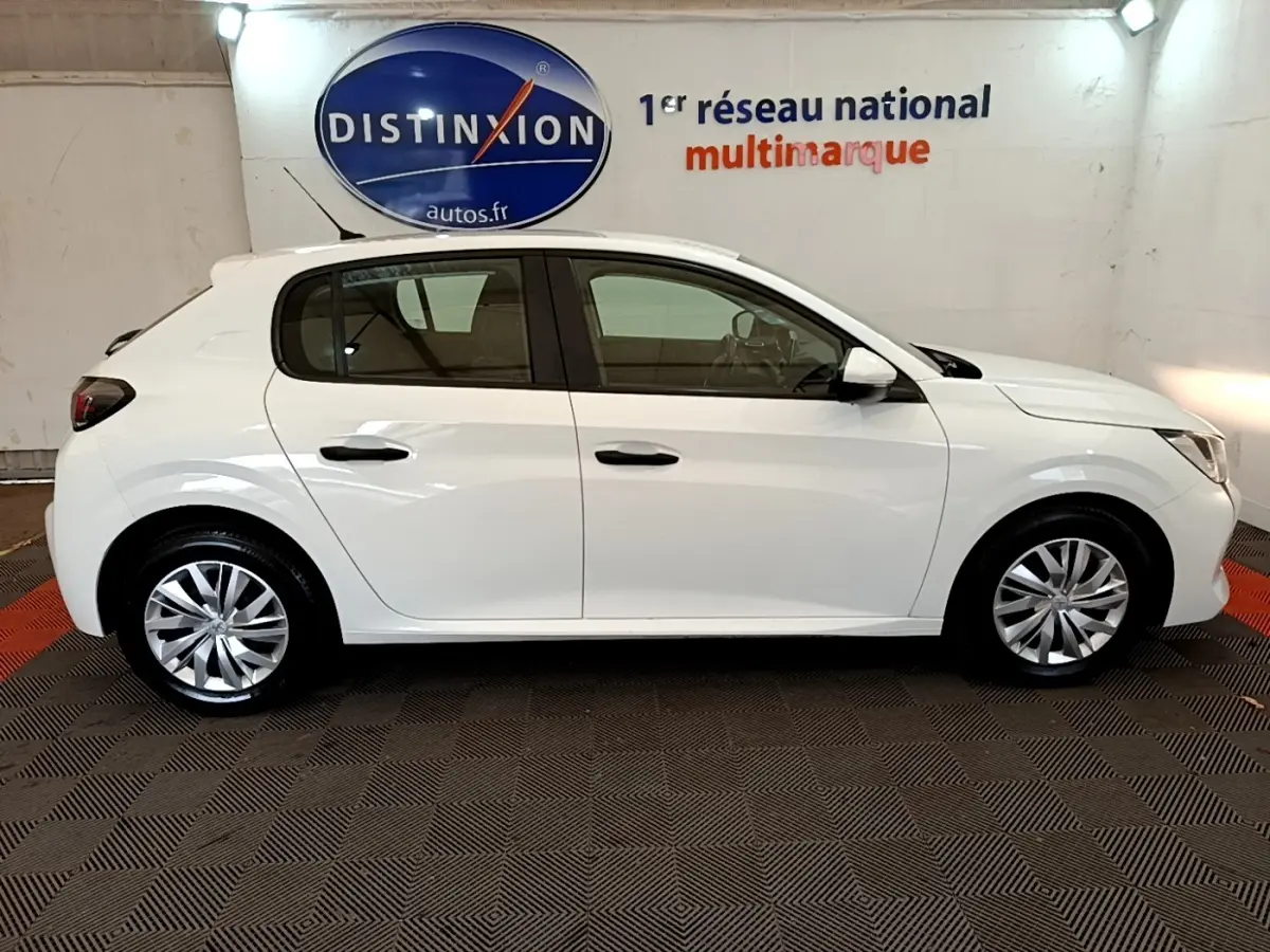 Peugeot 208 blanche vue de profil côté gauche, avec jantes alliage et rétroviseurs blancs en intérieur showroom.