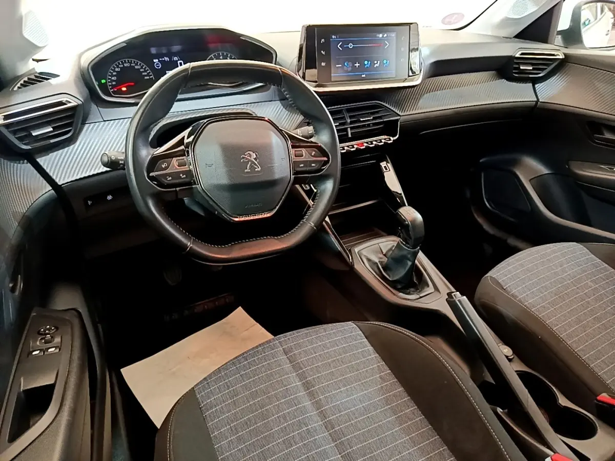 Intérieur de la Peugeot 208 1.2 PT 75 S&S Premium 2021, vue avant centrée sur le volant compact et l’écran tactile.