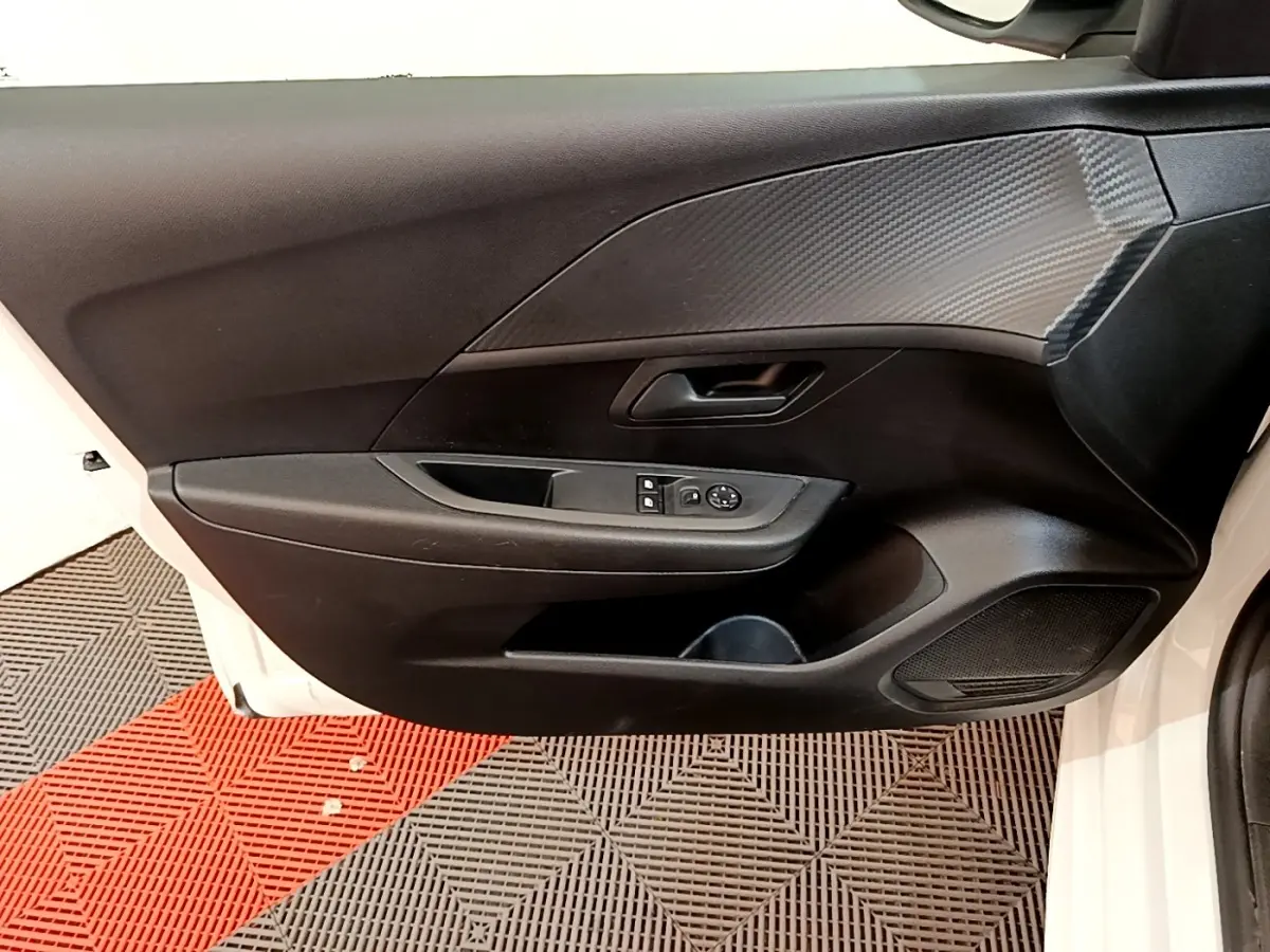 Vue intérieure de la porte avant gauche d'une Peugeot 208 blanche, avec commandes des vitres et revêtement noir texturé.