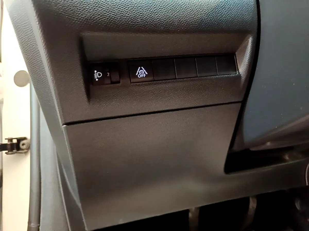 Détail des commandes de réglage des phares et d'activation de l'assistance au maintien de voie dans une Peugeot 208 blanche, vue côté conducteur.