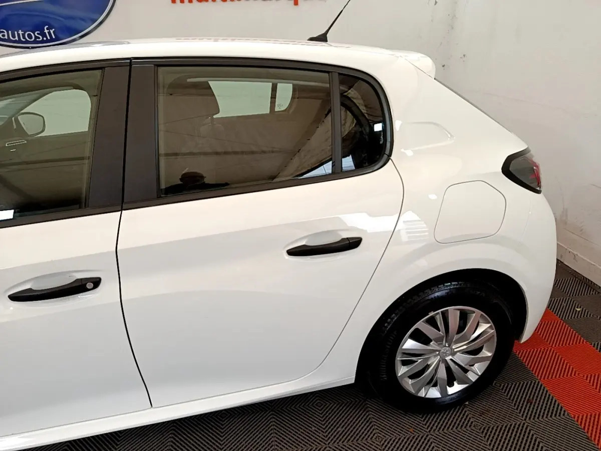 Vue latérale côté droit d'une Peugeot 208 blanche, mettant en valeur la porte arrière et la roue arrière.