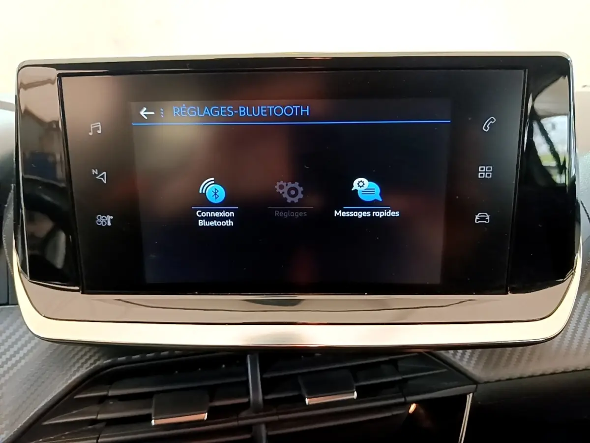Écran tactile central noir affichant les réglages Bluetooth dans l'habitacle d'une Peugeot 208 blanche.