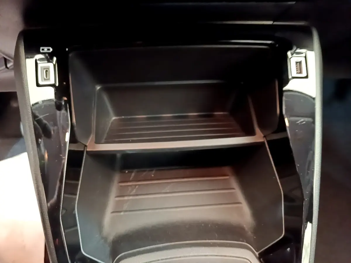 Gros plan sur le rangement central noir de la Peugeot 208 1.2 PT 75 S&S Premium, avec ports USB visibles.