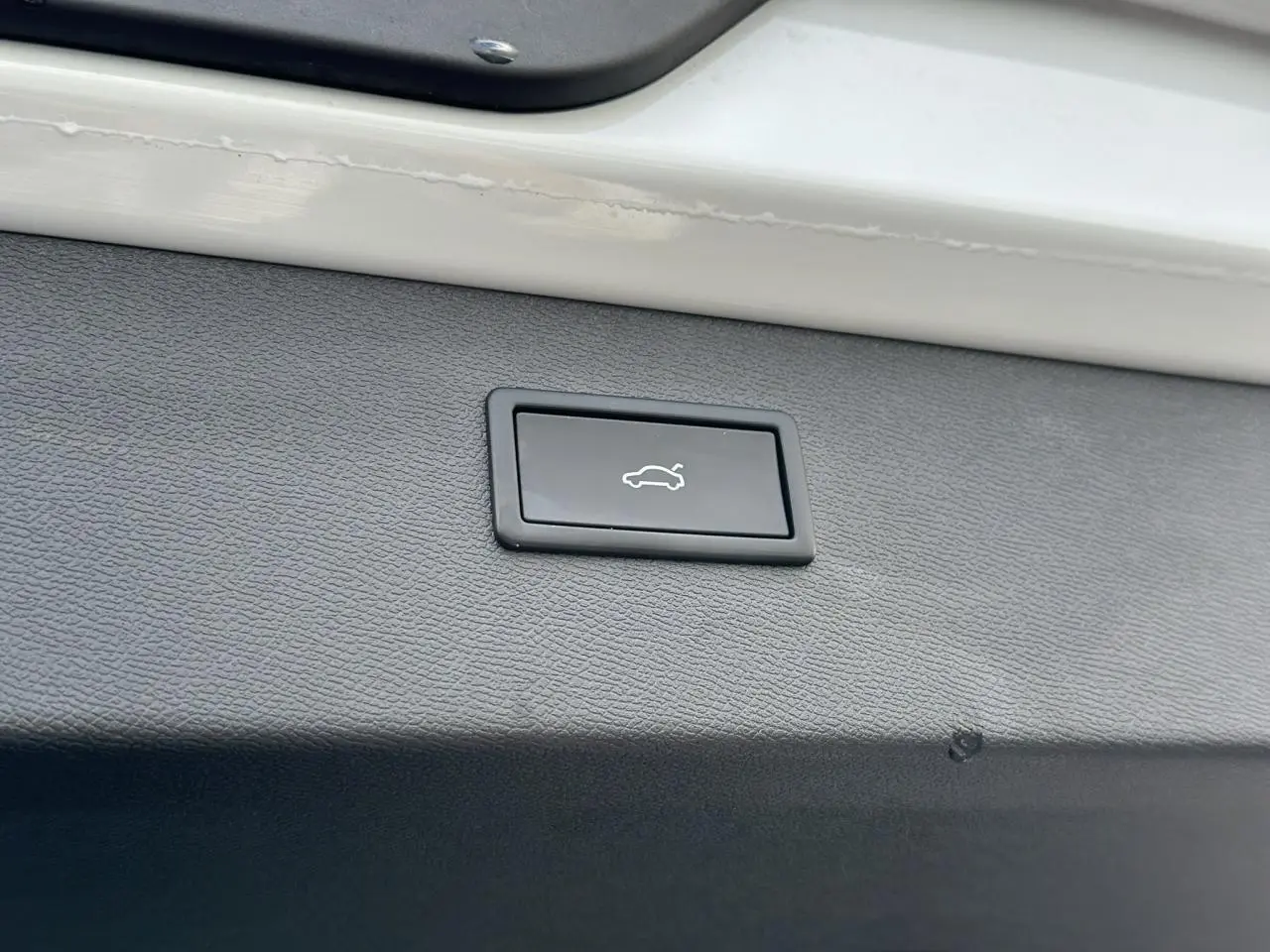 Bouton d'ouverture de coffre sur la garniture intérieure blanche du hayon d'un CUPRA Formentor blanc Neige.