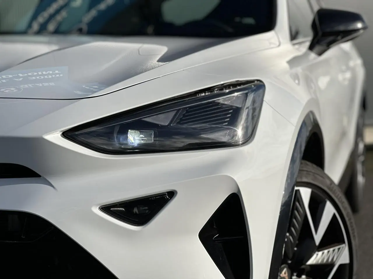 Gros plan sur l'avant droit blanc neige d'une CUPRA Formentor, mettant en valeur le phare Tri-LED et la jante alliage 19'' Sandstorm.