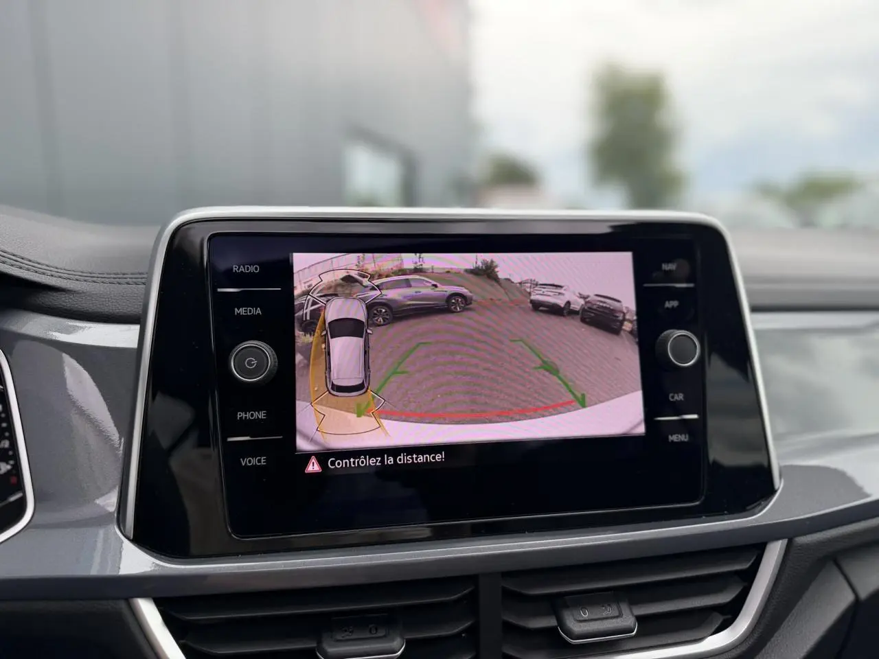 Écran tactile intérieur montrant la caméra de recul du Volkswagen T-Roc argenté, vue de face du tableau de bord.