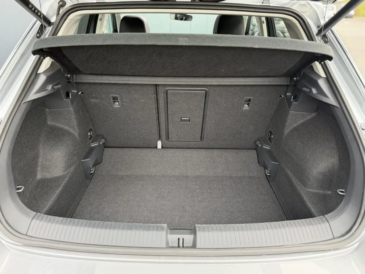 Coffre ouvert vue arrière d’un Volkswagen T-Roc argent Pyrite, montrant l’espace de chargement et la tablette cache-bagages.
