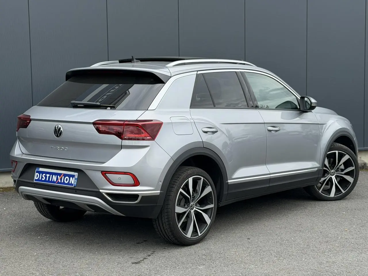 Vue 3/4 arrière droite du Volkswagen T-Roc argent Pyrite avec jantes alliage 19 pouces et vitres arrière surteintées.