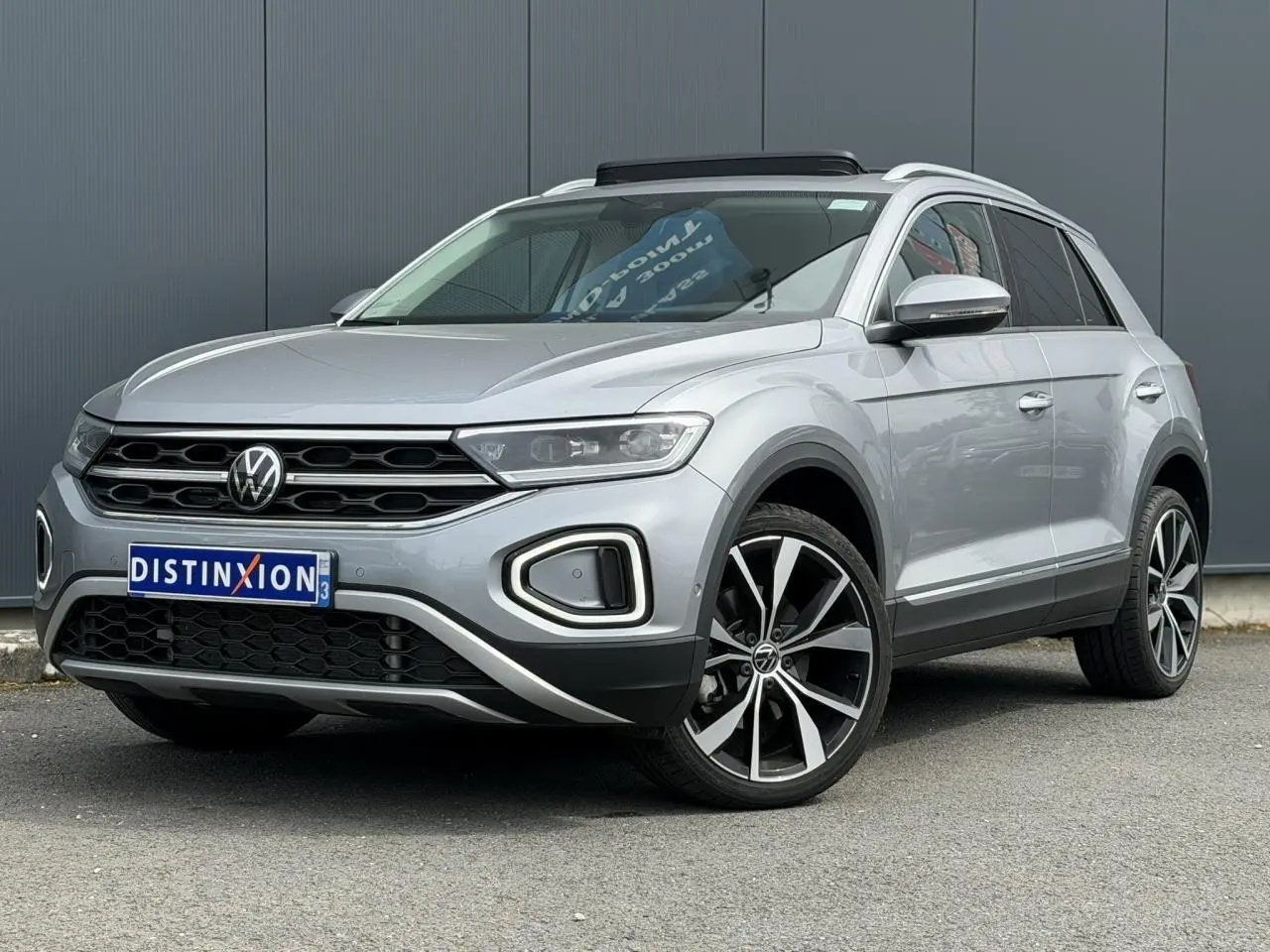 Volkswagen T-Roc 1.5 TSI argent pyrite, vue 3/4 avant droit, jantes alliage 19 pouces et toit ouvrant.