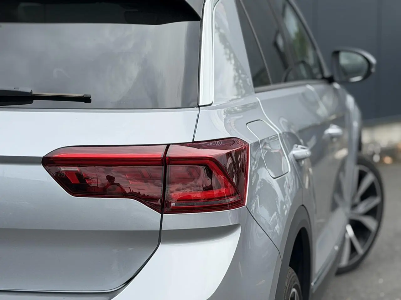 Vue 3/4 arrière droite du Volkswagen T-Roc 2024 argent pyrite avec feux arrière LED et jantes alliage 19 pouces.