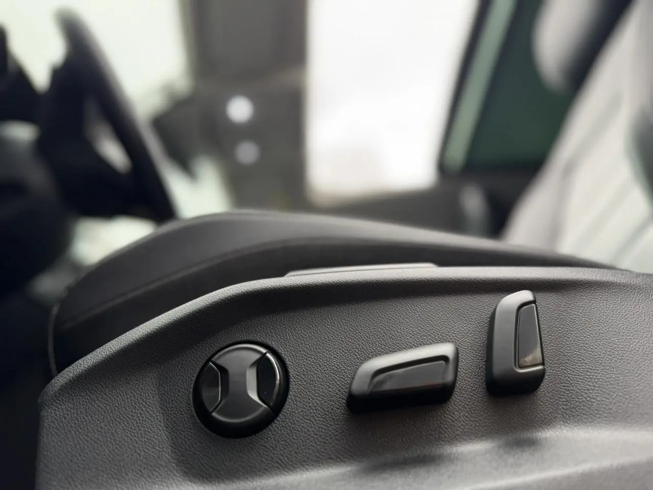 Gros plan sur les commandes électriques de réglage du siège conducteur du Volkswagen T-Roc 1.5 TSI argent Pyrite.