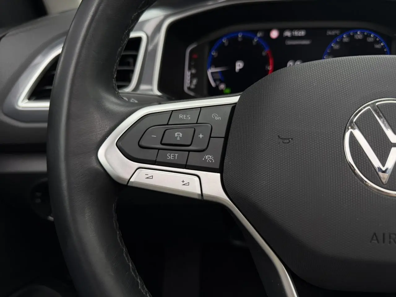 Gros plan sur le volant multifonction en cuir noir du Volkswagen T-Roc 2024, avec commandes de régulateur de vitesse.