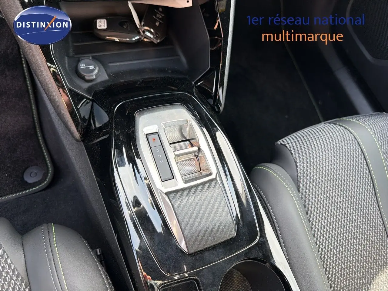 Gros plan sur la console centrale du Peugeot 2008 gris Artense, mettant en valeur la commande de boîte automatique et les sièges en cuir noir.