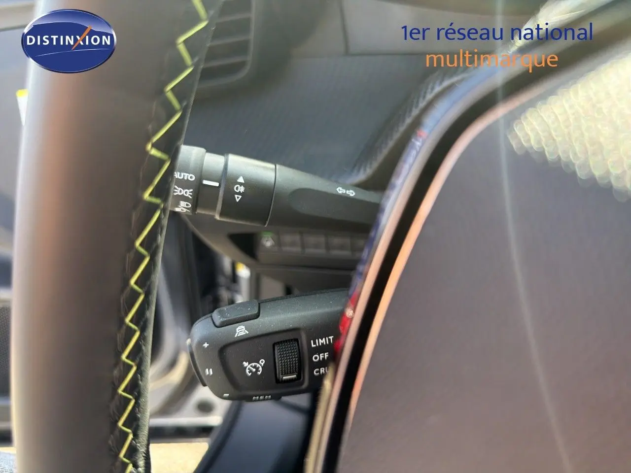 Détail du volant avec commandes de régulateur et commodo d’éclairage dans un Peugeot 2008 gris Artense toit noir.