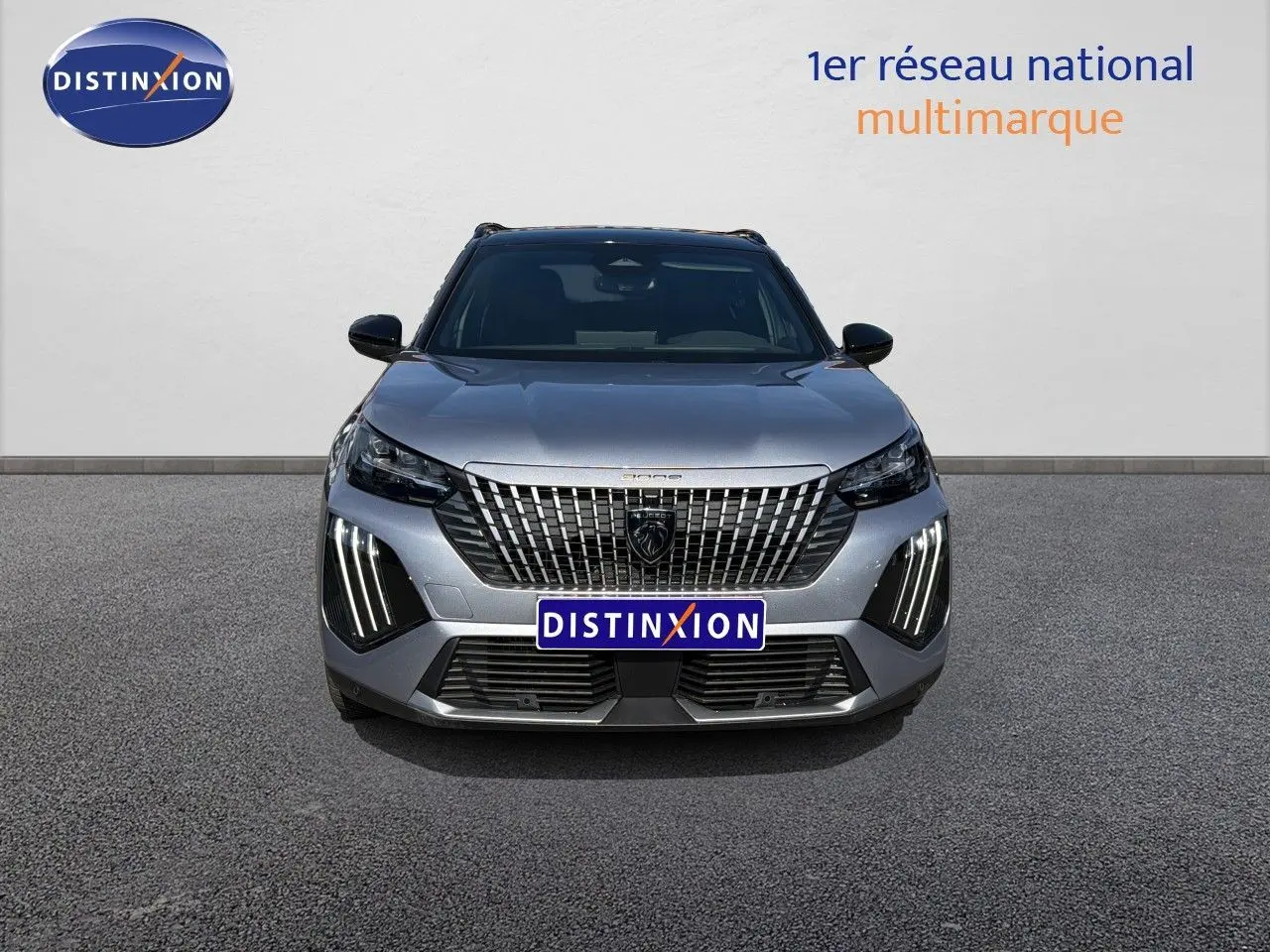 Vue frontale d'un Peugeot 2008 gris Artense avec toit noir, mettant en valeur la calandre distinctive et les feux LED verticaux.