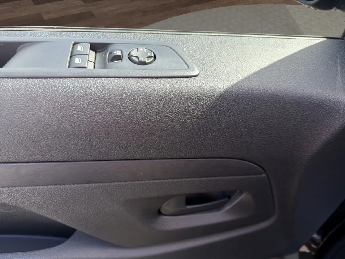 Gros plan sur la porte intérieure côté conducteur du Citroën Jumpy gris foncé avec commandes électriques des vitres et rétroviseurs.
