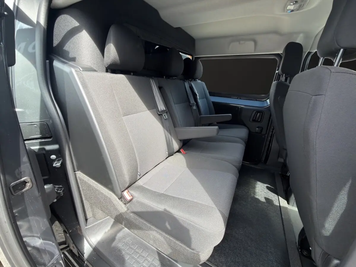 Vue intérieure côté gauche de la banquette arrière grise du Citroën Jumpy 2026 avec accoudoirs et ceintures visibles.