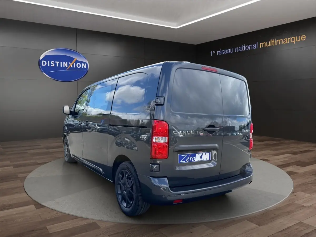 Vue 3/4 arrière droite d'un Citroën Jumpy gris foncé avec portes arrière pleines dans un showroom.