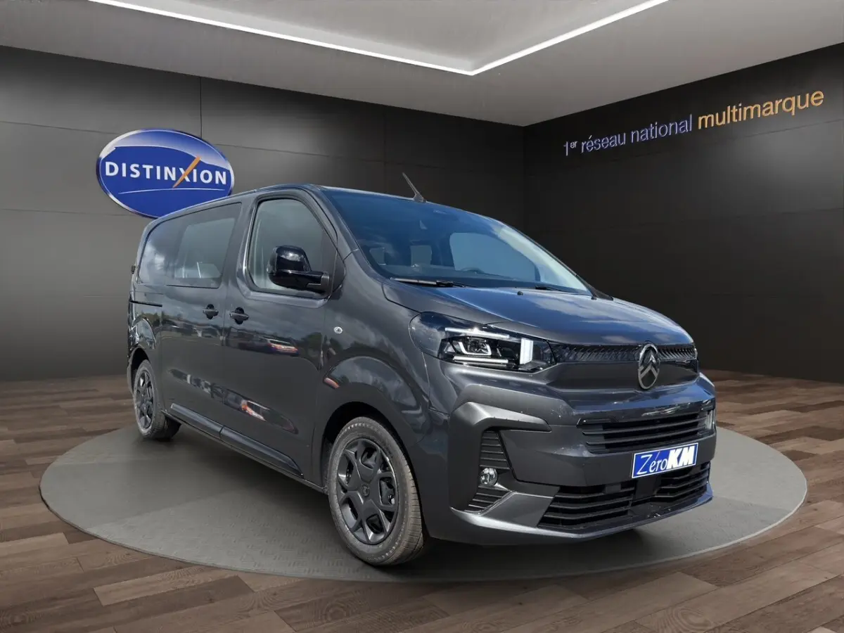 Vue 3/4 avant droit d'un Citroën Jumpy gris foncé avec calandre noire et jantes sombres en showroom.