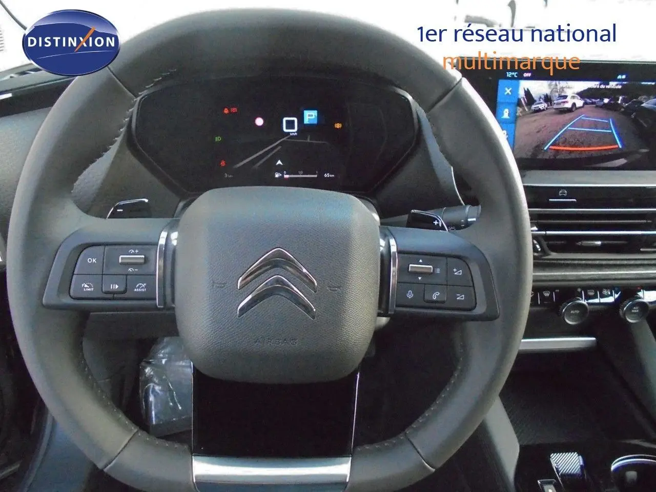 Volant cuir du Citroën C5 X 2022 avec commandes intégrées et écran affichant la caméra de recul en arrière-plan.