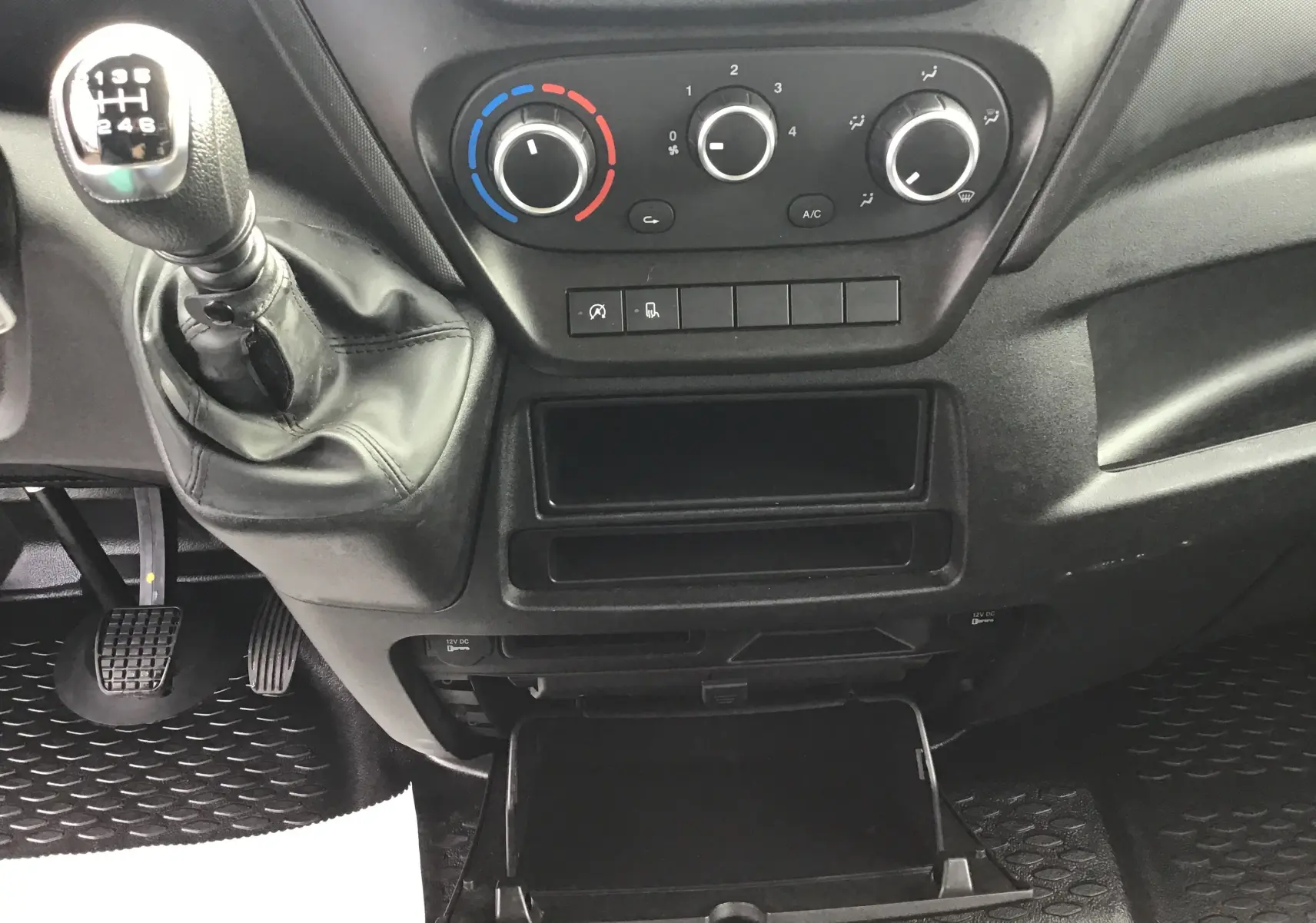 Intérieur du tableau de bord de l'Iveco Daily Fourgon 2022, avec levier de vitesses manuel et commandes de climatisation.