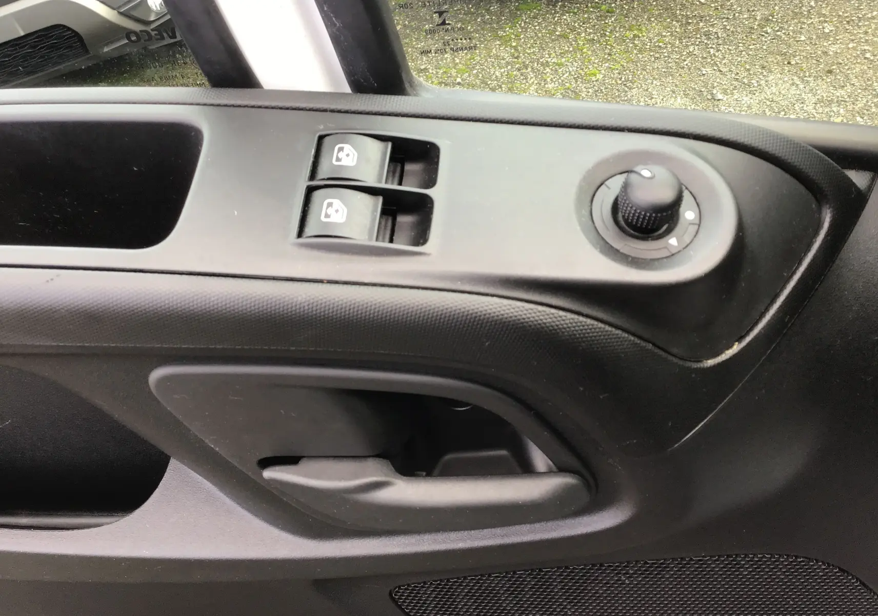 Gros plan sur la commande des vitres électriques et le réglage des rétroviseurs côté conducteur d'un Iveco Daily blanc.