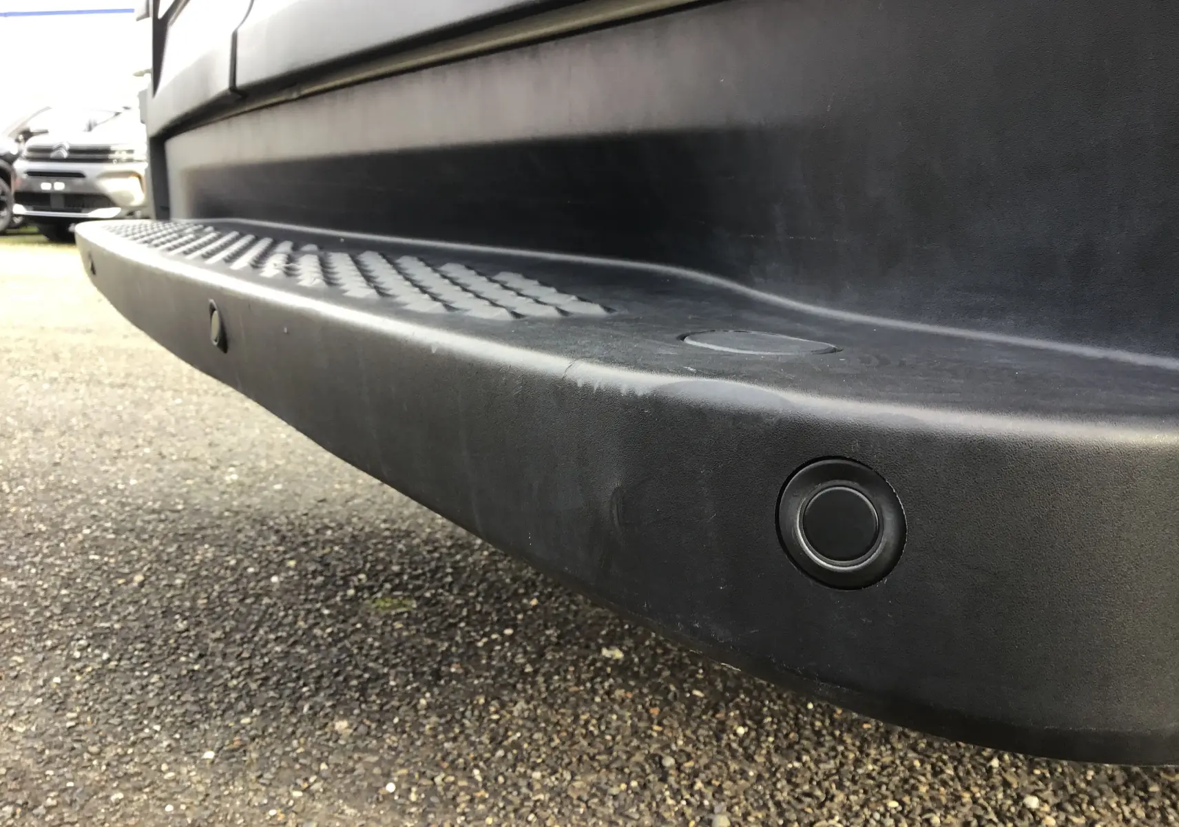 Gros plan sur le marchepied arrière noir du fourgon blanc Iveco Daily 35S16, soulignant le capteur de recul intégré.