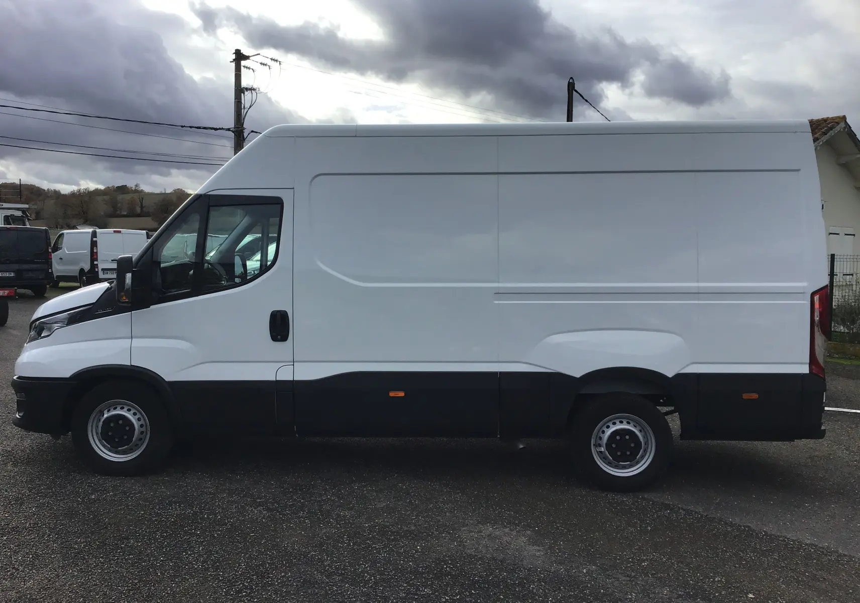 Profil latéral gauche d'un fourgon Iveco Daily blanc 2022 avec marchepied arrière et partie inférieure noire.