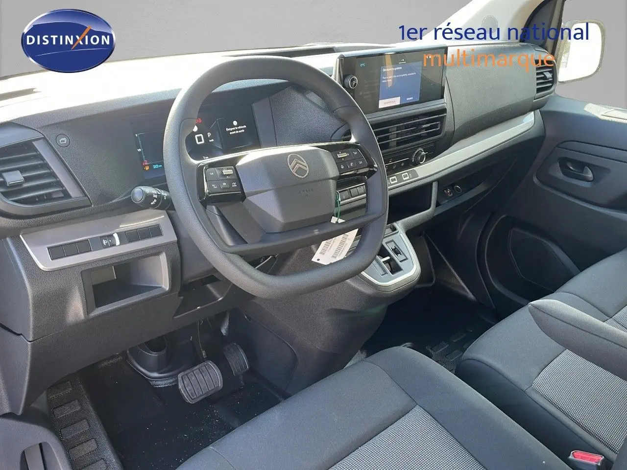 Vue intérieure côté conducteur du Citroën Jumpy Fourgon XL 2025, tableau de bord moderne avec volant multifonction et sièges gris.