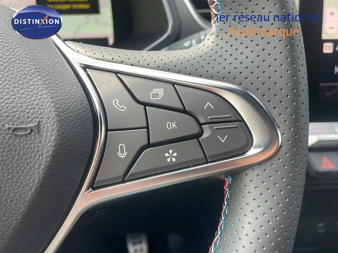 Gros plan sur les commandes au volant en cuir perforé gris avec surpiqûres tricolores du Renault Captur hybride 2025.