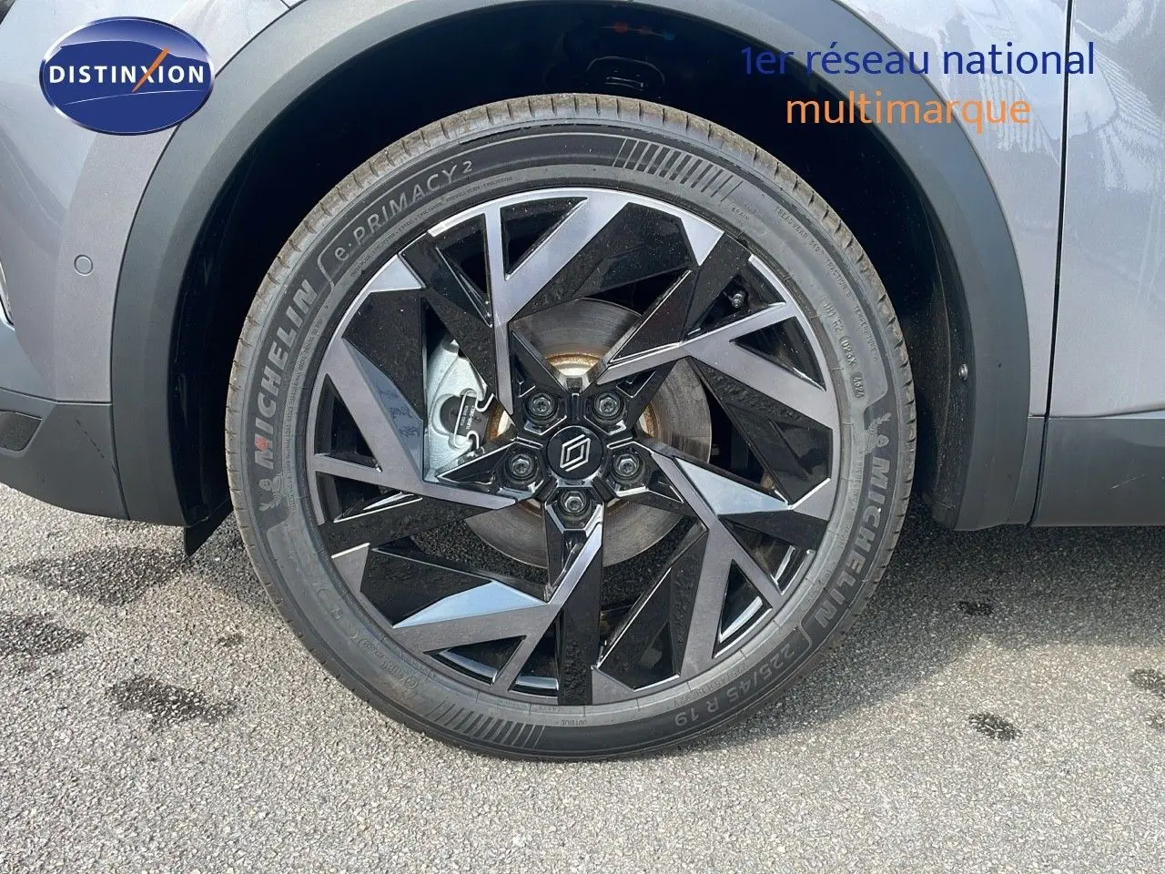 Gros plan sur la roue avant gauche du Renault Captur gris Cassiopée métal avec jante noire au design géométrique.