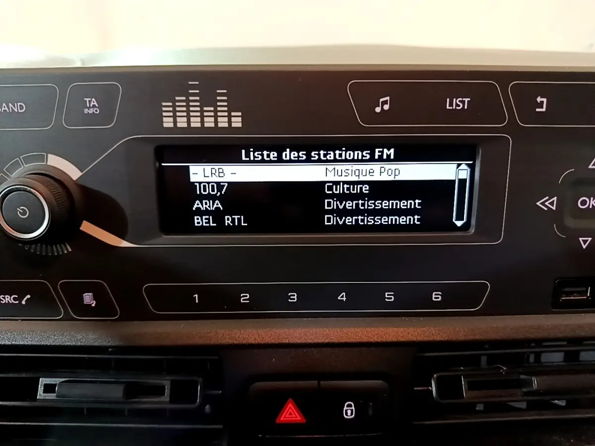 Gros plan sur l'écran radio et le tableau de bord noir du Citroën Berlingo blanc, version Club 2021.