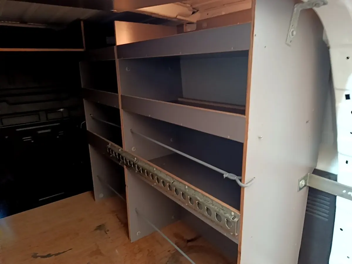 Vue intérieure du compartiment de chargement du Citroën Berlingo blanc, montrant les étagères de rangement en bois.