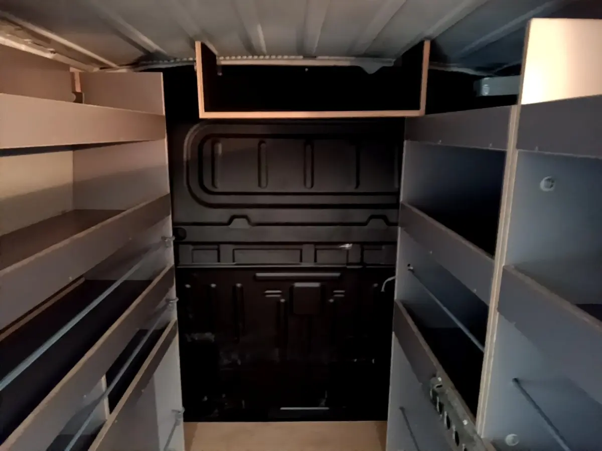 Vue intérieure arrière du Citroën Berlingo blanc 2021 avec cloison pleine et étagères de rangement grises.