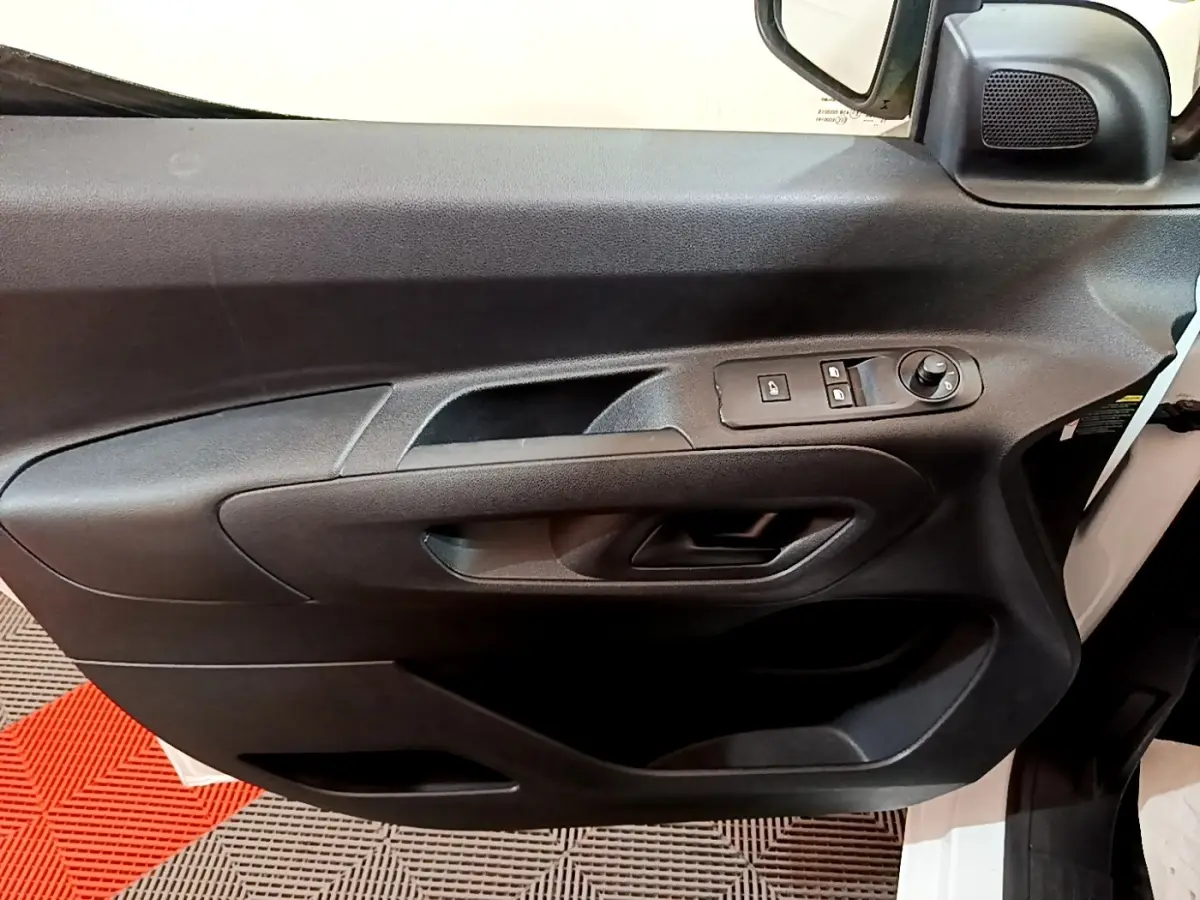 Gros plan sur la porte avant gauche noire du Citroën Berlingo blanc, avec commandes de vitres et rétroviseur électrique.