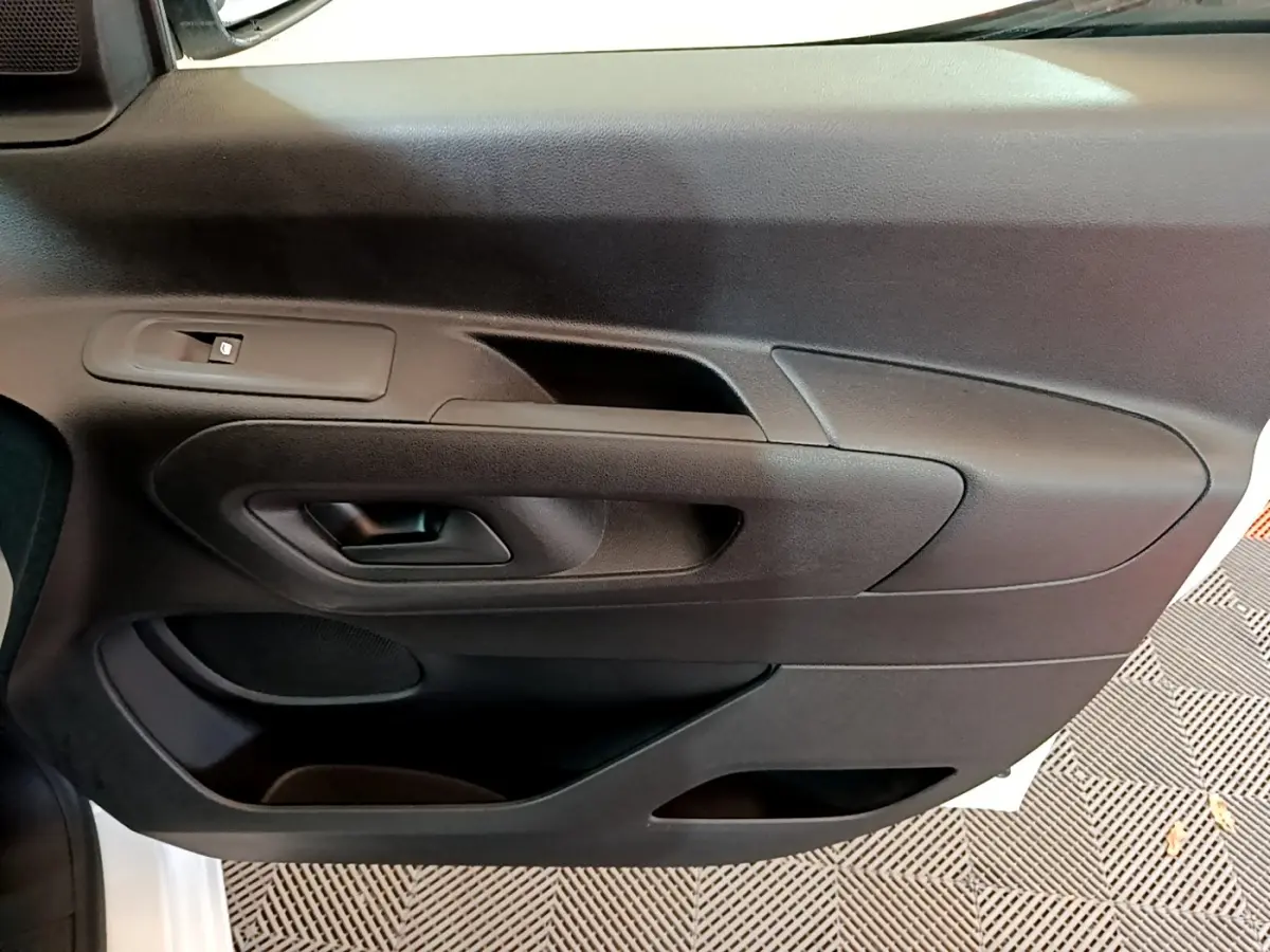 Vue rapprochée de la porte intérieure côté gauche du Citroën Berlingo blanc, avec poignée et commande de vitre.