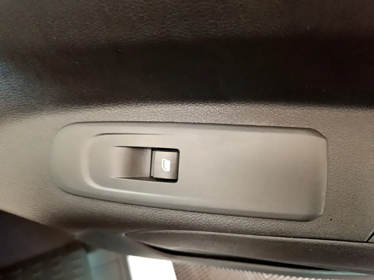 Gros plan sur le bouton de commande de vitre électrique noir dans l'habitacle du Citroën Berlingo blanc.