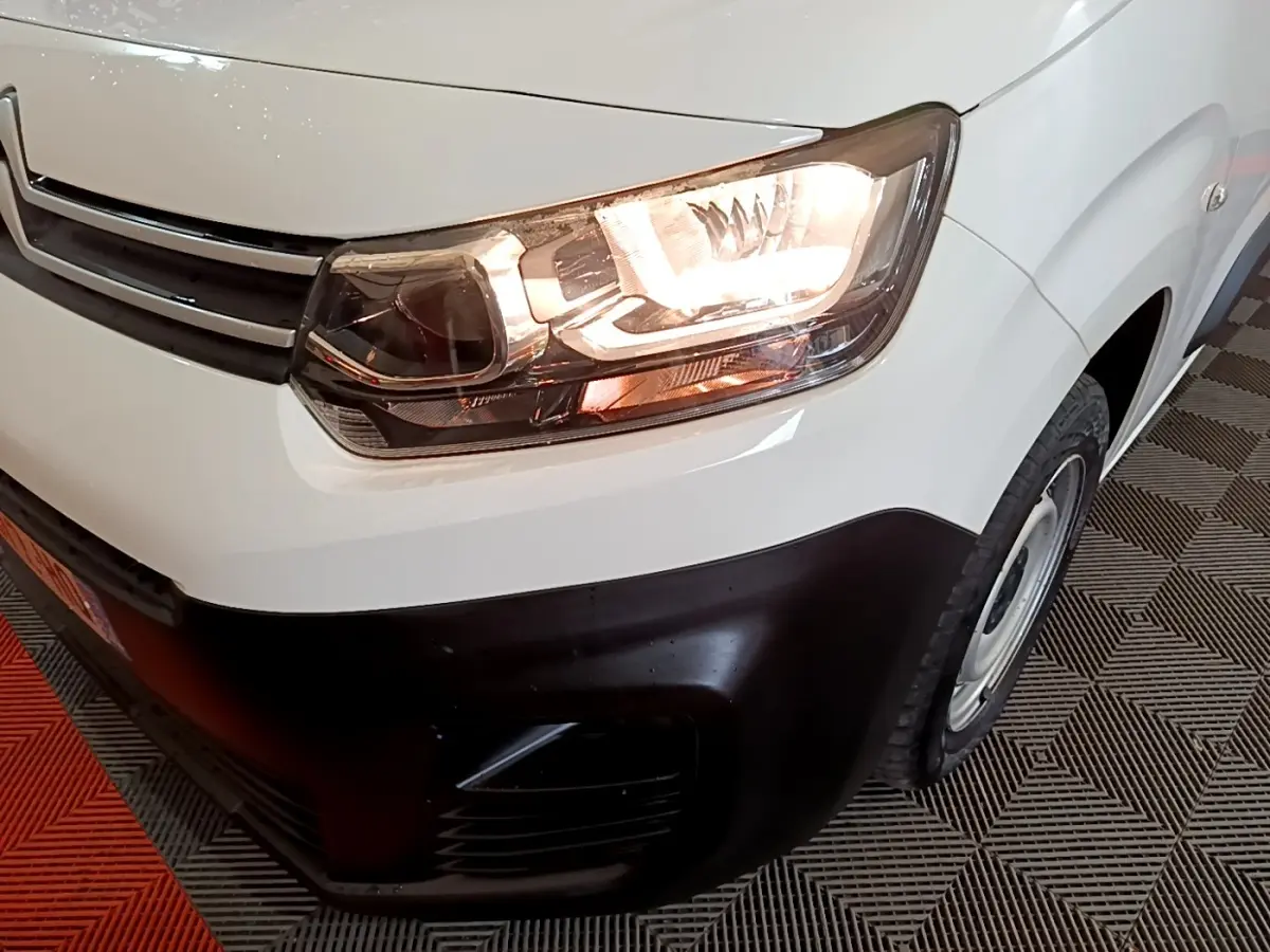 Gros plan sur l'avant droit d'un Citroën Berlingo blanc 2021 avec phare allumé et pare-chocs noir.