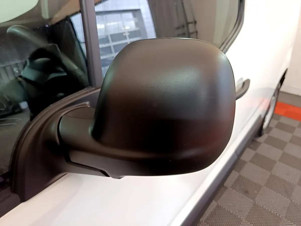 Rétroviseur noir en gros plan côté gauche du Citroën Berlingo blanc, vue rapprochée sur la portière avant.