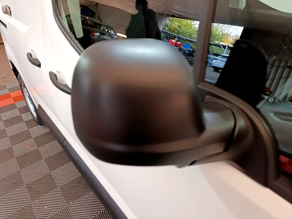 Rétroviseur noir en gros plan côté gauche d'un Citroën Berlingo blanc, vue latérale avant du véhicule.