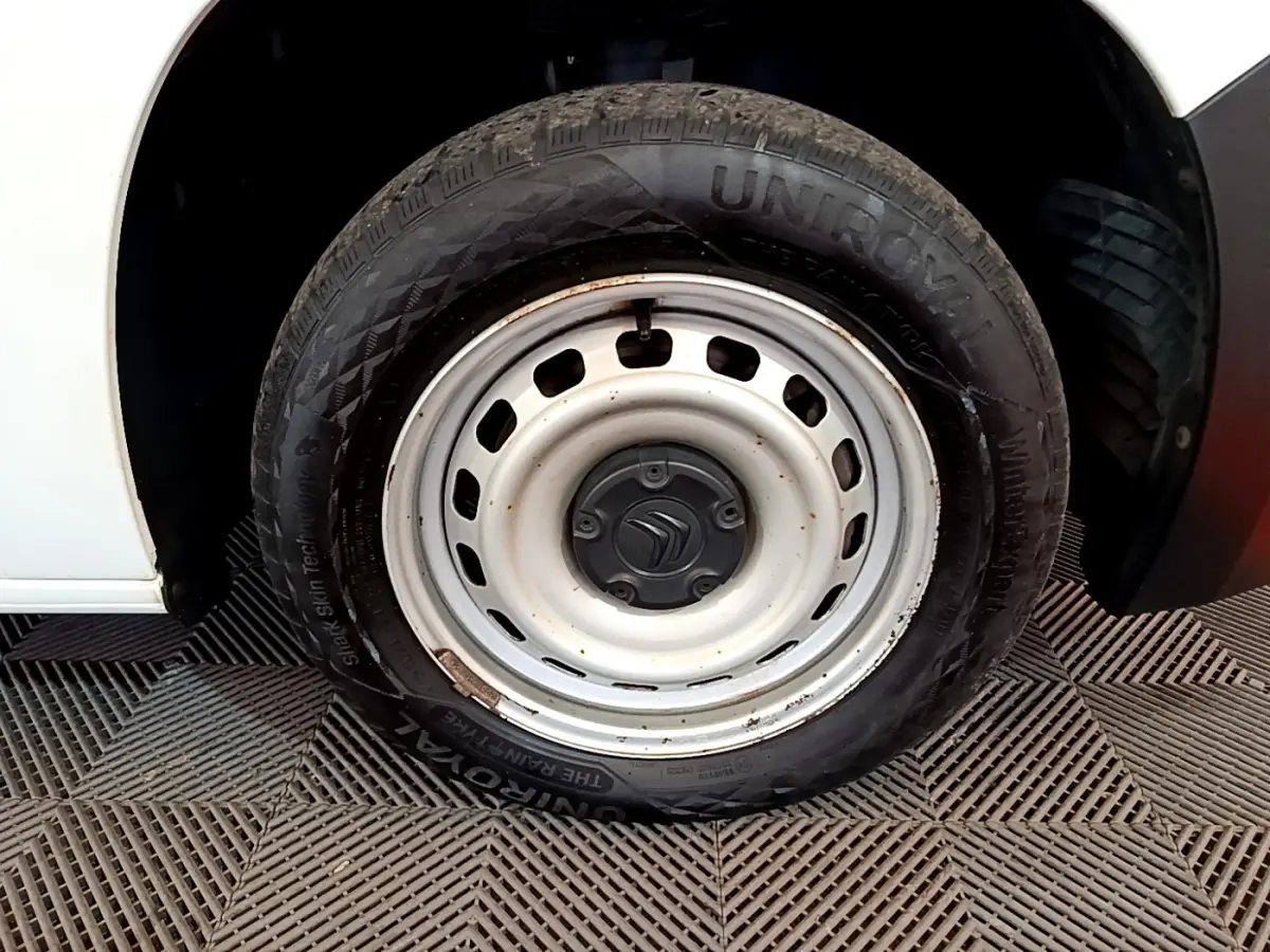 Gros plan sur la roue acier blanche avant droite d’un Citroën Berlingo blanc, avec logo Citroën au centre.