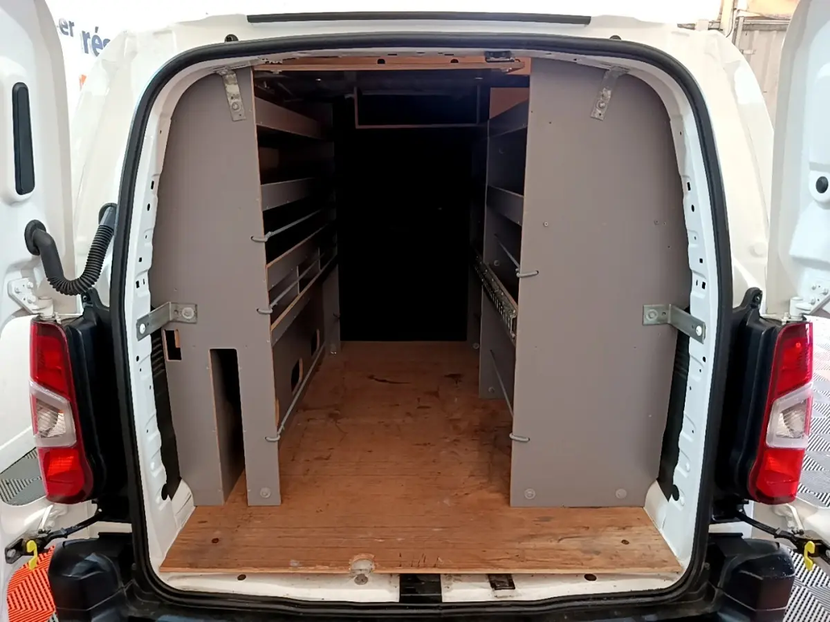 Vue arrière du Citroën Berlingo blanc 2021 avec portes ouvertes dévoilant un aménagement intérieur en bois et étagères grises.