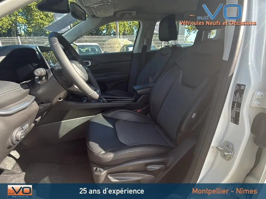 Vue intérieure côté conducteur du Jeep Compass blanc 2024, mettant en valeur le siège en cuir noir et l'accoudoir central.