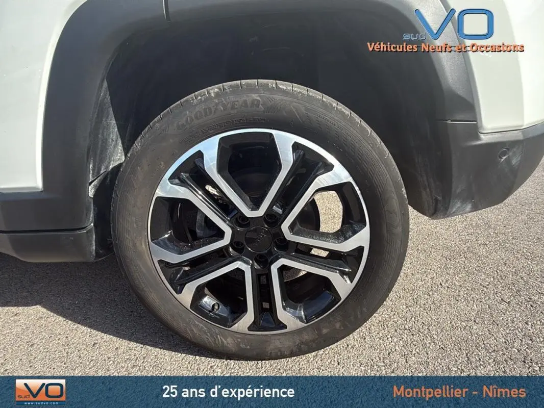 Gros plan sur la roue avant droite d’un Jeep Compass blanc 2024 avec jante alliage 18 pouces bicolore.