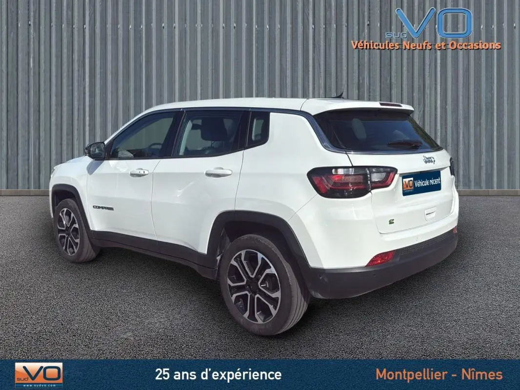 Jeep Compass blanc vue 3/4 arrière côté droit, jantes alliage 18 pouces et vitres teintées visibles.