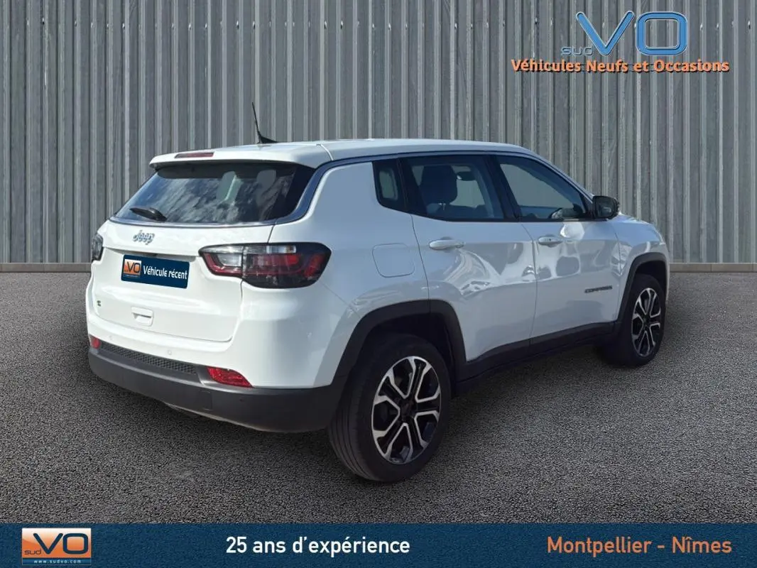 Vue 3/4 arrière droite d'un Jeep Compass blanc 2024 avec jantes alliage 18 pouces et vitres teintées.